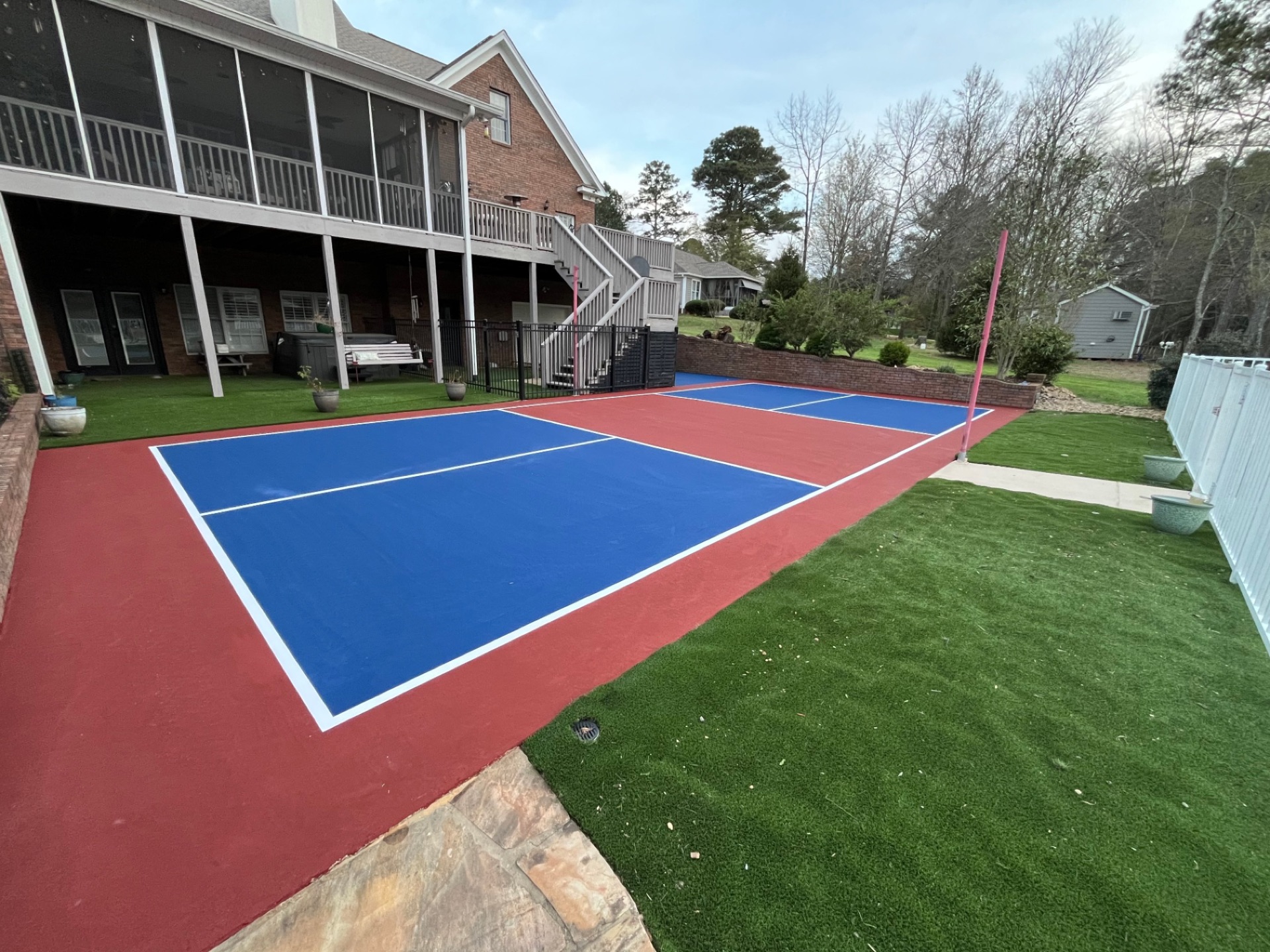Finished backyard pickleball court in Tennessee with blue playing surface and red surround