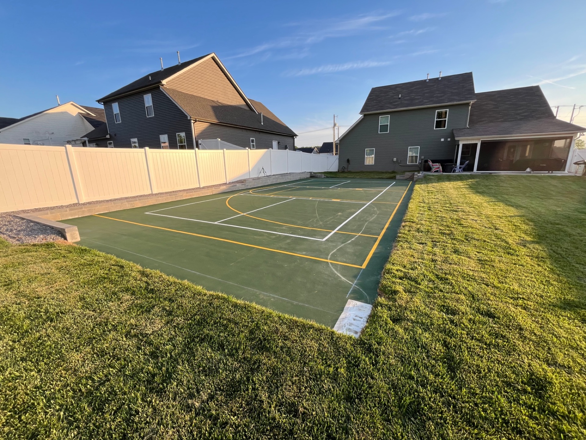 A finished residential pickleball court with fencing and surrounding landscaping
